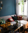 Lampada da tavolo con volto astratto in metallo nero su tavolino vetro in soggiorno colorato con parete blu e cuscini decorativi